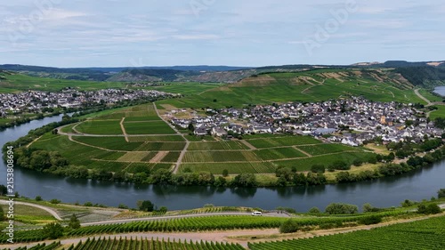 Idyllische Panorama-Luftaufnahme der berühmten Moselschleife bei Trittenheim, umgeben von grünen Weinbergen und sanften Hügeln unter leicht bewölktem Sommerhimmel.