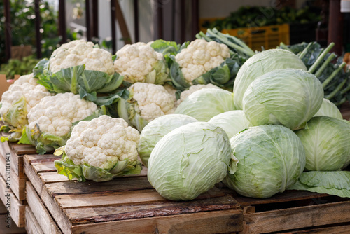 Canvas Print Fresh heads of white cauliflower Brassica oleracea var botrytis and green cabbages stacked on rustic wooden crates at a local farmer market outdoor counter during daylight, Warsaw, Poland, Europe