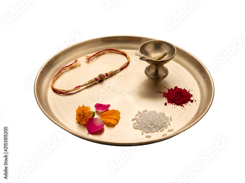 Minimal Raksha Bandhan puja thali with traditional rakhi, brass diya, kumkum, rice and flowers isolated as a transparent PNG festival asset.