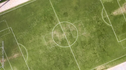 High angle aerial drone view flying over a green football field with marked white lines