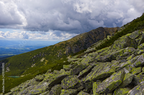 Foto Epic alpine landscape with lichen-covered rocks in foreground, a tarn, and deep valley in the High Tatra Mountains
