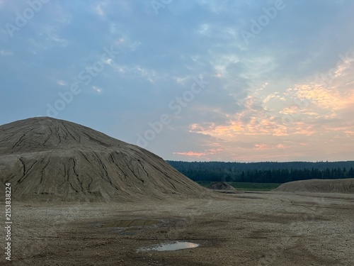 Large Gravel Hill With Exposed Stone, Loose Aggregate and Rugged Natural Terrain in an Open Outdoor Landscape During Sunset