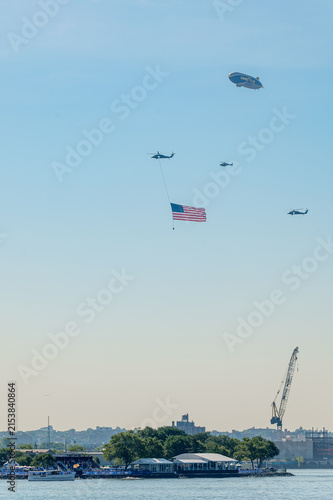 Принти на полотні Helicopters carry American flag below Goodyear blimp on July 4
