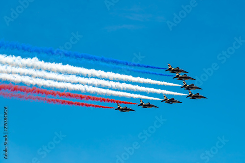 Jets fly paints French tricolor above New York. Seven Alpha Jets fly in arrow formation, releasing blue, white and red smoke across a clear sky.