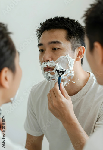 Young asian man shaving his...