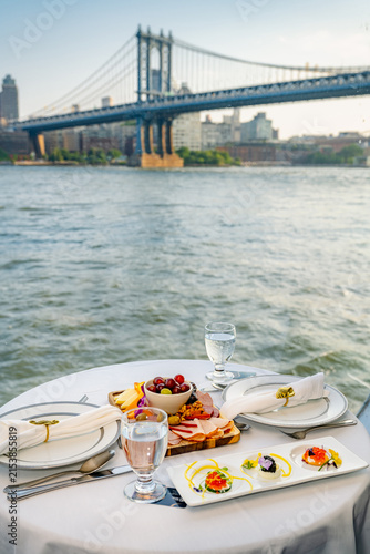 Dining with a view of the Manhattan Bridge on the East River in New York City. People enjoy a meal by the water with a view of the Manhattan Bridge in New York City.