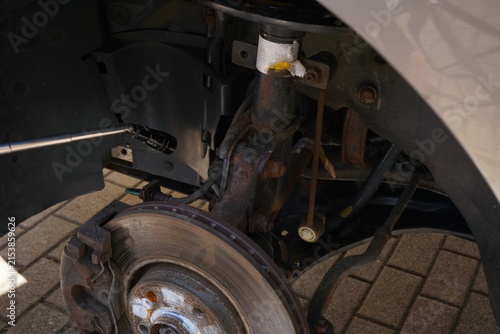 Close-up of a worn brake rotor and suspension assembly inspected with a flexible tool during automotive repair, maintenance and vehicle safety service.
