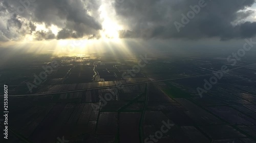 Aerial view of dark storm clouds casting dramatic light over flooded plains after rain.