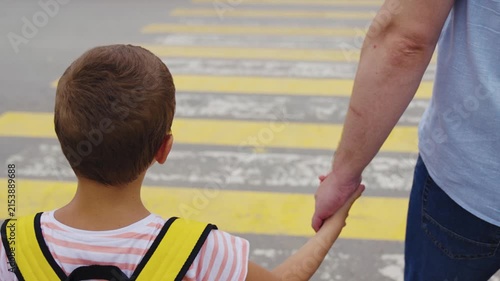 Back to school safety, Parent and child walking, Boy with backpack crossing street, Safe pedestrian behavior, Child learning road safety, Crossing the road with dad, Family moment outdoors, Holding