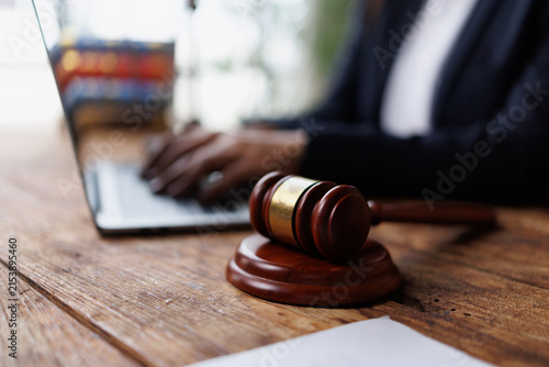 Gavel on a desk with a lawyer typing on a laptop, symbolizing online legal work, justice, and remote law services