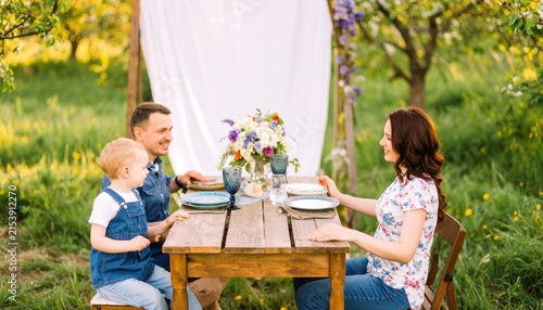 Happy Family Enjoying Outdoor Picnic Dinner in Sunny Garden