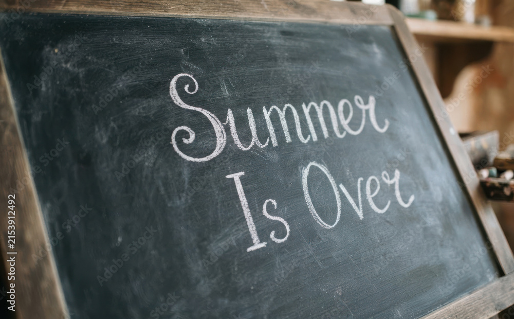 Fototapeta premium Chalkboard with the handwritten text Summer Is Over on a dark background, concept of end of vacation and back to school season