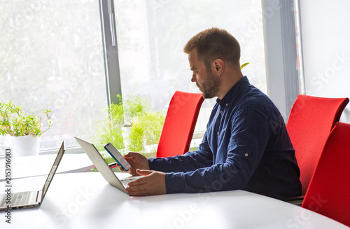 Canvastavla professional man working in the office at a desk using a smartphone and laptop