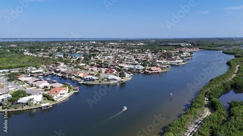 Single boat headed up Sykes Creek with waterfront homes on canals on one side and the Ulumay Wildlife Sanctuary on the other in Merritt Island, Florida.