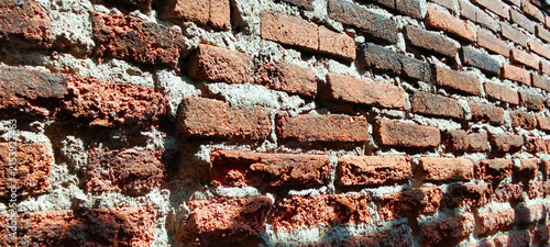 Weathered red brick walls with cement mortar.