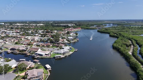 Single boat headed down Sykes Creek with waterfront homes on canals on one side and the Ulumay Wildlife Sanctuary on the other in Merritt Island, Florida.