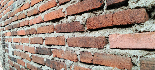 Rustic red brick wall texture against a rough cement mortar background.
