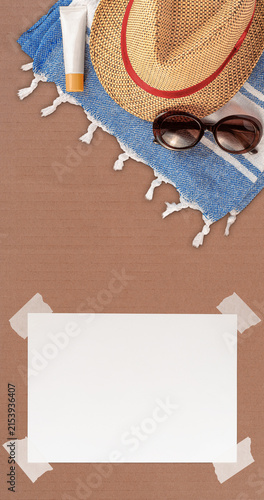 Summer Wallpaper with Straw Hat, Towel, Sunglasses, Protection Cream and White Blank Free Space Paper Sheet with Adhesive Tape on Cardboard Sheet. File with Clipping Path.