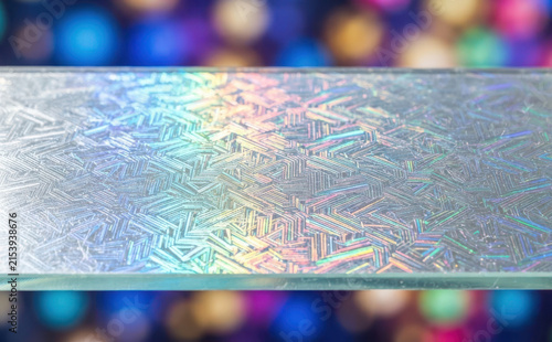 Holographic diffraction grating glass slide dispersing rainbow light on colorful bokeh background for optical physics and laser experiments