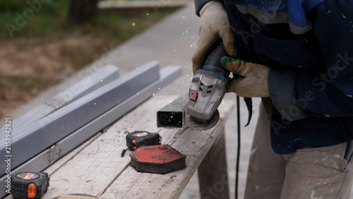Canvas Print Worker using angle grinder cutting metal square tubing with sparks flying on out