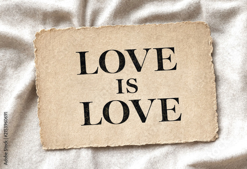 Vintage paper card with love is love message on soft fabric background perfect for romance themes