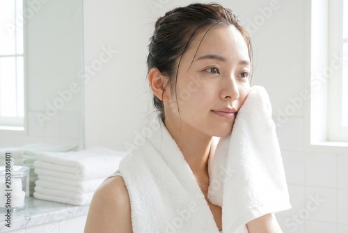 白いタオルで顔を拭く若い女性（スキンケア・保湿・美容・洗顔）