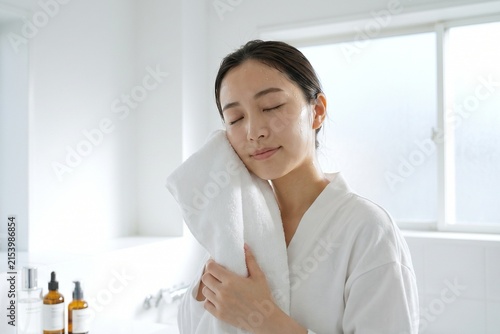 白いタオルで顔を拭く若い女性（スキンケア・保湿・美容・洗顔）