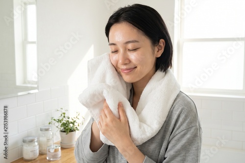 白いタオルで顔を拭く若い女性（スキンケア・保湿・美容・洗顔）