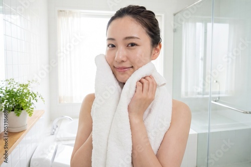 白いタオルで顔を拭く若い女性（スキンケア・保湿・美容・洗顔）