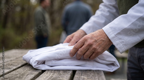 Hands rolling a white bath towel neatly on a bed, representing hotel housekeeping, hospitality service and professional room preparation. Perfect for business and lifestyle stock photography.