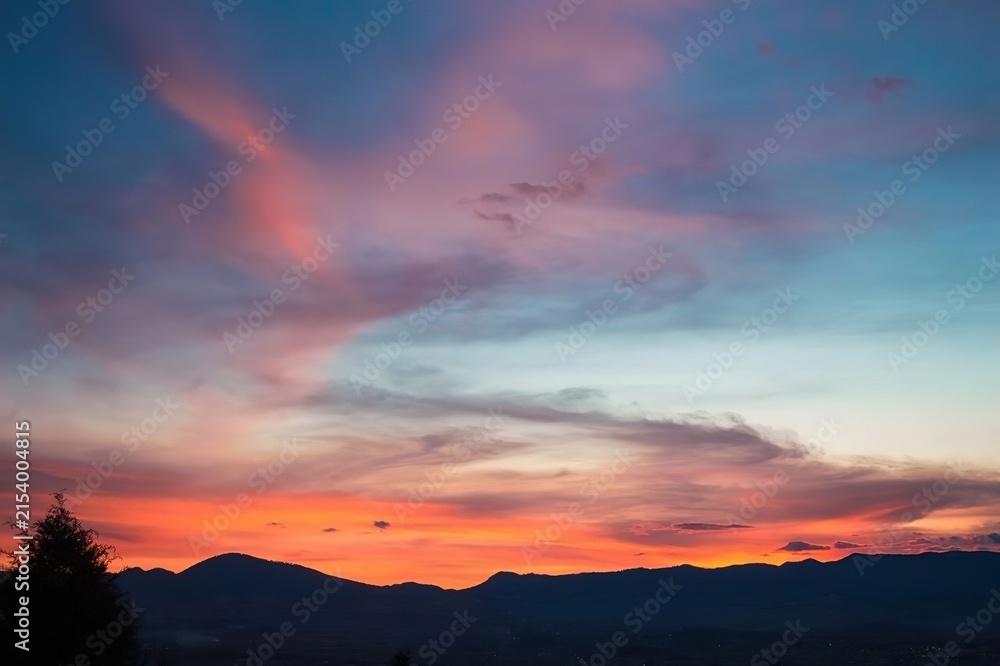 Fototapeta premium Panoramic Sunset Sky Deep Blue Vibrant Pink Fiery Orange Distant Mountains Twilight Landscape