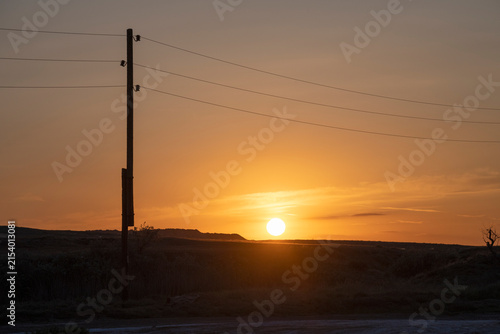 Obraz na plátne Pole with power line against the background of May sunset