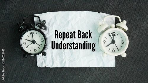 Chime clock and paper with the word Repeat back understanding. listening to someone, restating their message or instructions in your own words, and asking if you got it right.