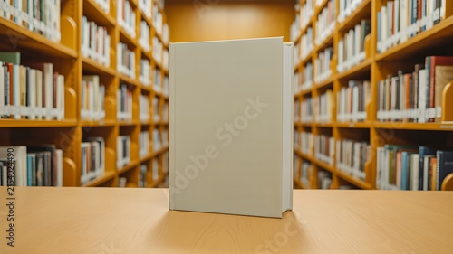 Blank book standing on a wooden table between library shelves