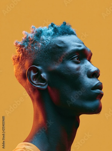 Man with blue dyed curly hair and dramatic lighting in profile