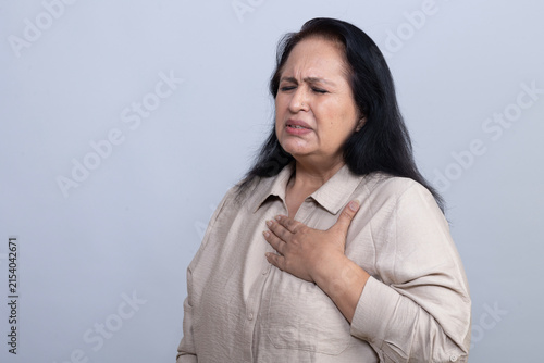 Konstfotografi Mature Indian woman holding her chest while experiencing apparent chest pain and discomfort, showing a distressed expression in a clean studio setting, representing a health and medical concern