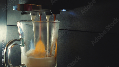 Fotografía Closeup of coffee machine dispensing espresso steamed milk into clear glass mug