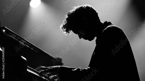 Musician playing piano in dramatic spotlight, silhouette of concentration