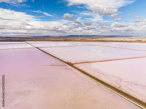 Aerial view of Bumbunga Lake with pink salt water pools separated by earthen embankments under a blue sky with scattered clouds in Wakefield Regional Council, South Australia, Australia.