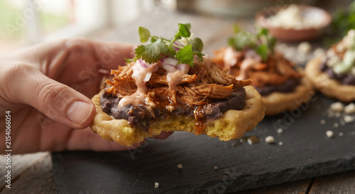 A focus-stacked, mouth-watering image capturing a bite taken out of a loaded sope, showing the contrast between the dense, chewy corn base and the savory toppings.