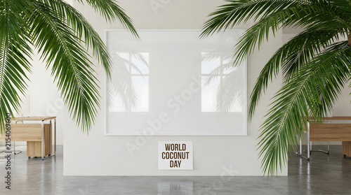 Blank white frame hanging on office wall with palm leaves for world coconut day display.