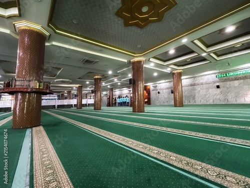 Large mosque interior with green carpets and golden pillars