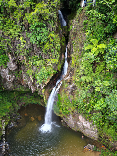 Aerial view of Cuetzalan's Breezes Waterfall, pristine water flowing through lush jungle foliage into a tranquil natural pool.