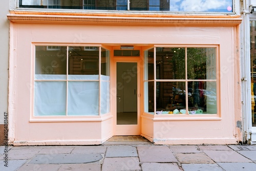 Pink wooden shopfront with large glass display windows and a central entrance, featuring a weathered paint texture for a boutique mockup and retail template