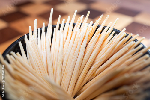 Fotografía Wooden toothpicks sticking out plastic jar macro shot, Pile of round wooden toothpicks