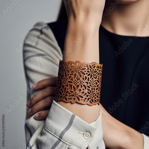 Woman wearing a wide brown leather cuff bracelet with floral patterns