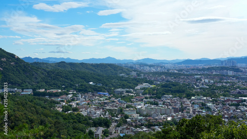Scenic wide landscape of Seoul featuring residential areas, distant city skyline, and beautiful mountain nature
