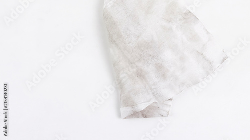 Bild auf Leinwand A close-up view of a used, dirty white paper tissue or wet wipe with dark stains and smudges, positioned on the right side against a clean white background with generous negative space
