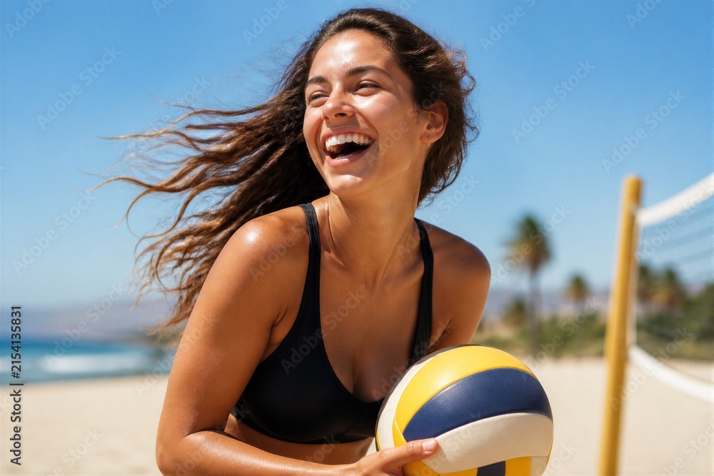 Fototapeta premium Young woman laughing while holding volleyball on sandy beach