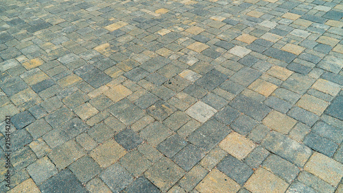 Paved ground shows a pattern of stones with different colors in a square layout